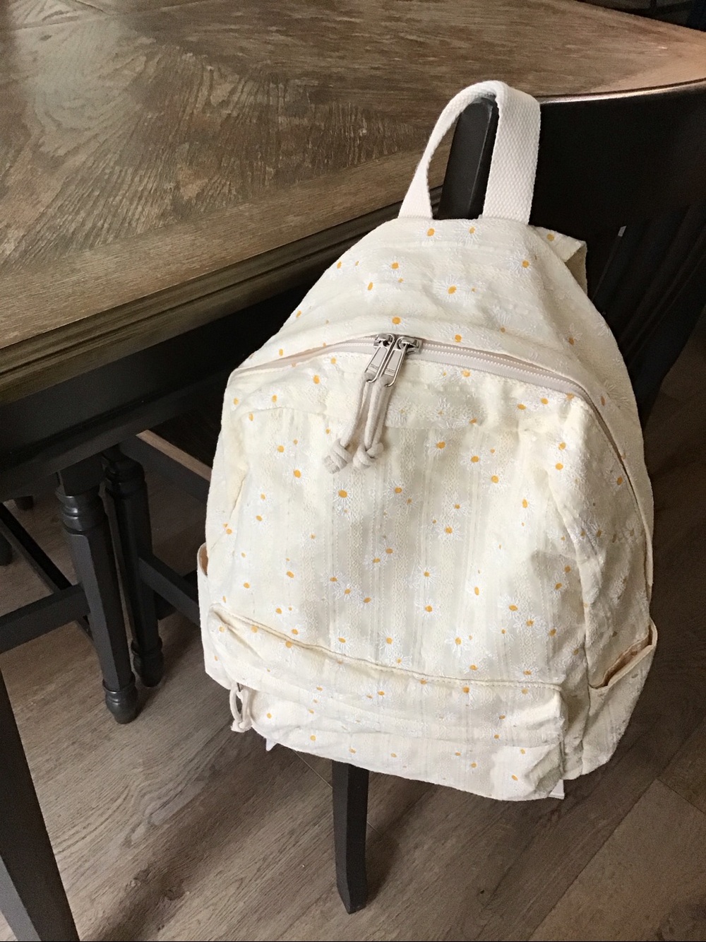 Lightweight cream-colored backpack with a delicate ditsy daisy print.